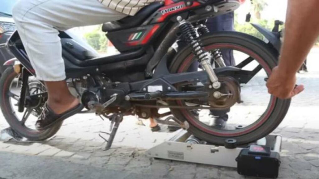 Un agent vérifie une moto sur un rouleau, illustrant le contrôle technique dont l'application a été reportée.