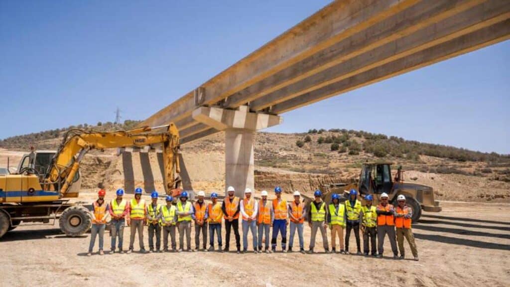 Vue du chantier de construction d’un pont sur Oued Kert, avec des poutres en béton précontraint et des engins de chantier en activité, dans le cadre du projet Nador West Med.