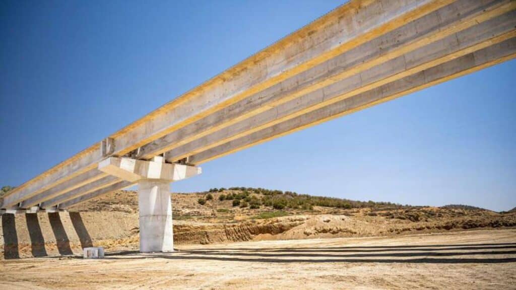 Vue du chantier de construction d’un pont sur Oued Kert, avec des poutres en béton précontraint et des engins de chantier en activité, dans le cadre du projet Nador West Med.