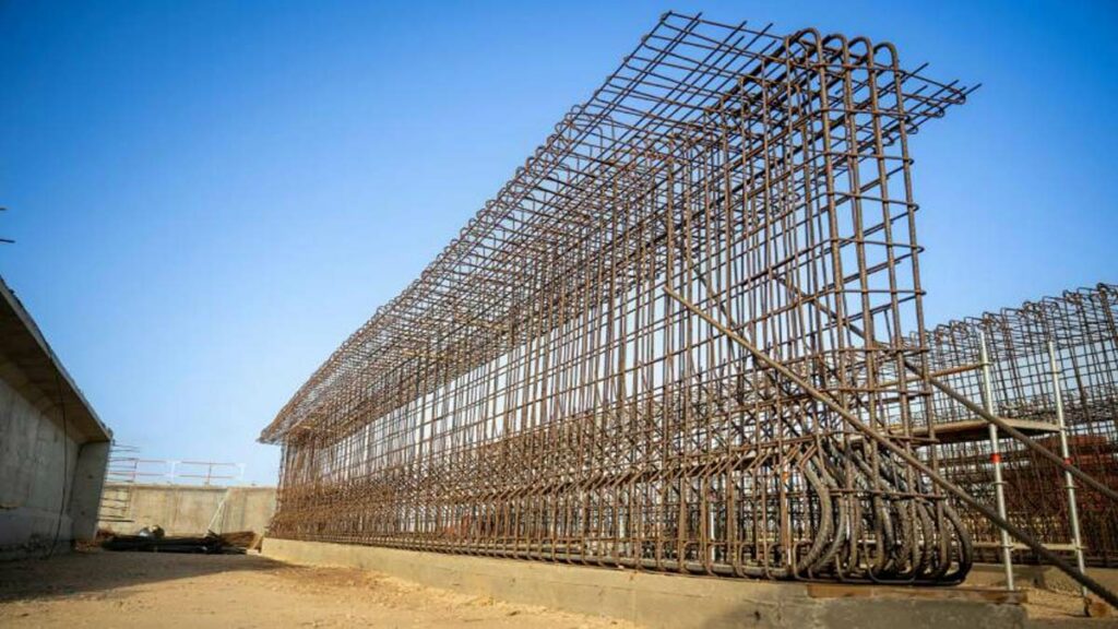 Vue du chantier de construction d’un pont sur Oued Kert, avec des poutres en béton précontraint et des engins de chantier en activité, dans le cadre du projet Nador West Med.