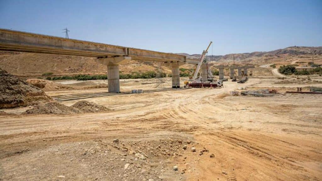 Vue du chantier de construction d’un pont sur Oued Kert, avec des poutres en béton précontraint et des engins de chantier en activité, dans le cadre du projet Nador West Med.