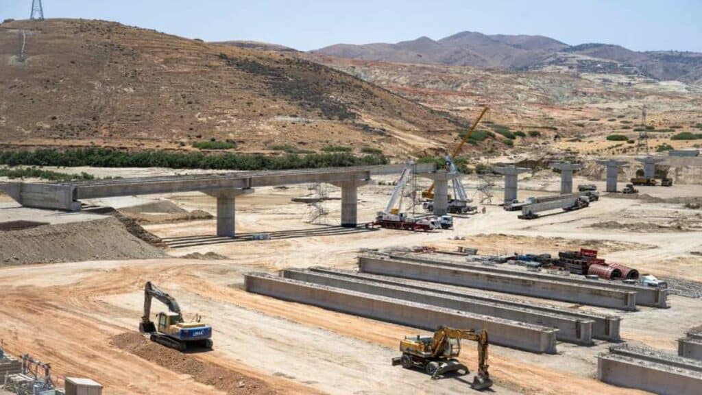 Vue du chantier de construction d’un pont sur Oued Kert, avec des poutres en béton précontraint et des engins de chantier en activité, dans le cadre du projet Nador West Med.