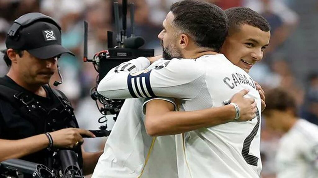 Un jeune marocain en survêtement du Real Madrid salue le public du stade Santiago Bernabéu, sous les applaudissements des joueurs et arbitres.