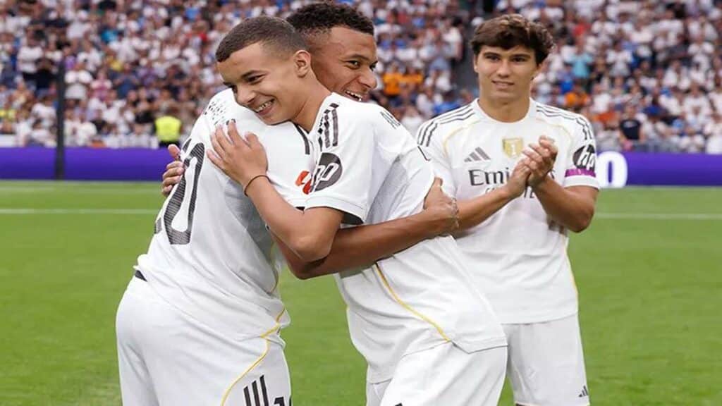 Un jeune marocain en survêtement du Real Madrid salue le public du stade Santiago Bernabéu, sous les applaudissements des joueurs et arbitres.